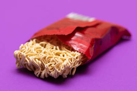 Opened Package with Uncooked Instant Noodles on Violet Background. Raw Pasta. Dry Asian Fast Food. Quick Lunchの写真素材