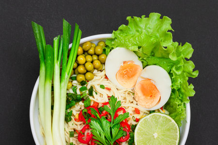 Beautiful Noodle Dish with Green Onions, Eggs, Green Pea, Red Hot Pepper, Greens and Lime on Sushi Mat. Instant Noodles with Vegetablesの写真素材