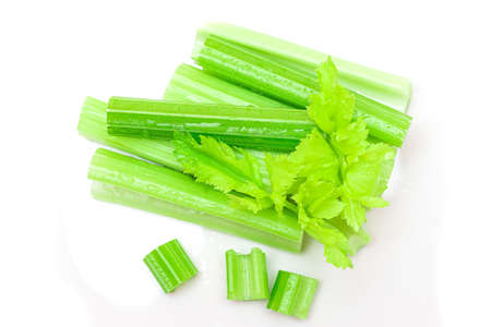 Fresh Chopped Celery Sticks and Slices with Leaves and Water Drops Isolated on White Background. Vegan and Vegetarian Culture. Raw Food. Healthy Diet with Negative Calorie Contentの写真素材
