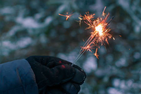 Burning Sparklers in a Hand Outdoors in Winter in Evening. New Year Celebration Partyの写真素材