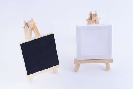 Two Wooden Easels Miniature with Blank Black and White Square Canvas for Artists and Painters - Mockup. Mini Wooden Stand with Clean Artboard on White Background, Copy Spaceの写真素材