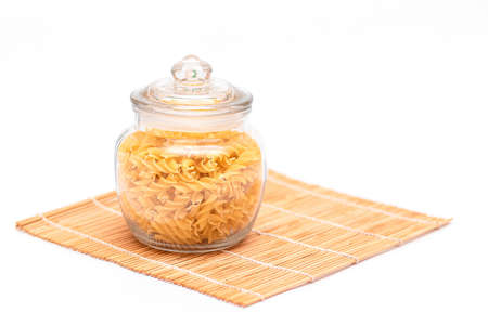 Uncooked Fusilli Pasta in Glass Jar on White Background. Raw and Dry Macaroni. Unhealthy and Fat Food. Italian Cultureの写真素材