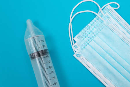 Safe Vaccine, Anti Vaccination Concept - Syringe in a Condom Lay on Blue Table in Clinic or Hospital. Mistrust of Vaccination. Natural Immunity. Skepticism About the Vaccine. Freedom and Human Rightsの写真素材