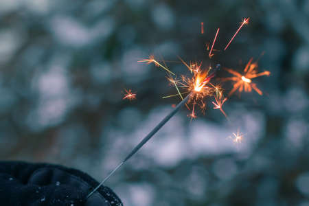 Burning Sparklers in a Hand Outdoors in Winter in Evening. New Year Celebration Partyの写真素材