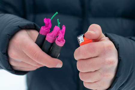Guy Sets Fire to the Flash Noise Firecrackers Outdoors in Winter at Daytime. Loud and Dangerous New Years Entertainment. Hooliganism with Pyrotechnics. Noise of Petards in Public Placesの写真素材