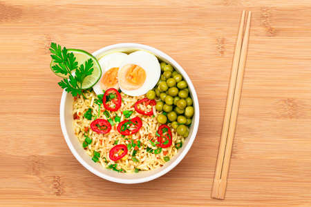 Beautiful Noodle Dish with Green Pea, Eggs, Red Hot Pepper and Greens on Bamboo Cutting Board....