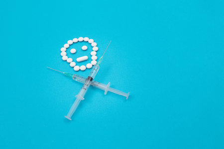 Dangerous Pharmaceutical Products or Unsafe Pills and Tablets - Skull or Death Symbol Made from White Pills and Syringes Lying on Blue Backgroundの写真素材