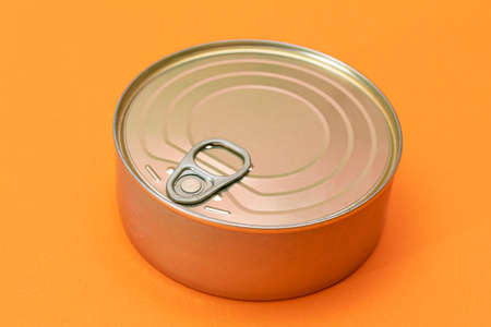 Unopened Tin Can with Blank Edge on Orange Background. Canned Food. Aluminum Can for Safe and Long Term Storage of Food. Steel Sealed Food Storage Containerの写真素材
