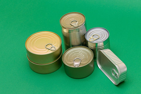 A Group of Stacked Tin Cans with Blank Edges on Green Background. Canned Food. Different Aluminum...