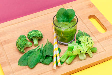 Fresh Green Smoothie of Apple, Celery, and Spinach in Glass Beaker with Yellow Cocktail Straw on...