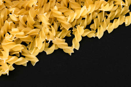 Uncooked Fusilli Pasta with Copy Space on Black Background. Raw and Dry Macaroni. Fat and Unhealthy Food - Flat Layの写真素材