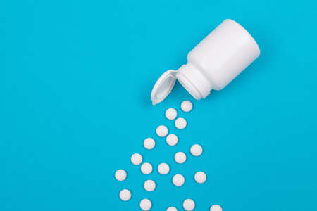 Global Pharmaceutical Industry and Medicinal Products - White Pills or Tablets Scattered from the Bottle, Lying on Blue Background, Top View, Flat Layの写真素材