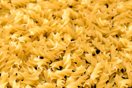 Uncooed Fusilli Pasta - Background. Texture of Bright Golden Dry Macaroniの写真素材