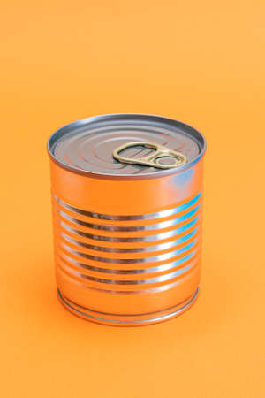 Unopened Tin Can with Blank Edge on Orange Background. Canned Food. Aluminum Can for Safe and Long Term Storage of Food. Steel Sealed Food Storage Containerの写真素材