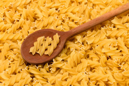 Uncooked Fusilli Pasta with Wooden Spoon. Raw and Dry Macaroni. Unhealthy and Fat Food. Italian Cultureの写真素材
