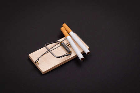 Tobacco Addiction and the World Corporations Trap - Cigarettes in Wooden Mousetrap on Black Backgroundの写真素材