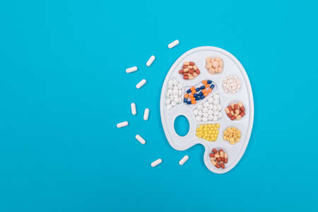 Global Pharmaceutical Industry and Medicinal Products - Different Colored Pills, Tablets and Capsules on White Art Palette Lying on Blue Background, Flat Layの写真素材