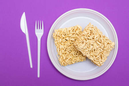 Uncooked Instant Noodles on White Plate. Raw Pasta. Dry Asian Fast Food. Quick Lunchの写真素材