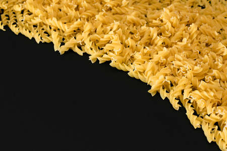 Uncooked Fusilli Pasta with Copy Space on Black Background. Raw and Dry Macaroni. Fat and Unhealthy Food - Flat Layの写真素材