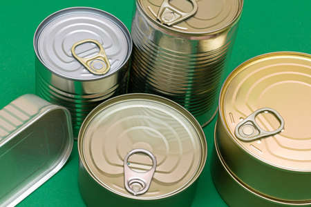 A Group of Stacked Tin Cans with Blank Edges on Green Background. Canned Food. Different Aluminum Cans for Safe and Long Term Storage of Food. Steel Sealed Food Storage Containersの写真素材
