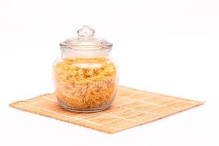 Uncooked Fusilli Pasta in Glass Jar on White Background. Raw and Dry Macaroni. Unhealthy and Fat Food. Italian Cultureの写真素材