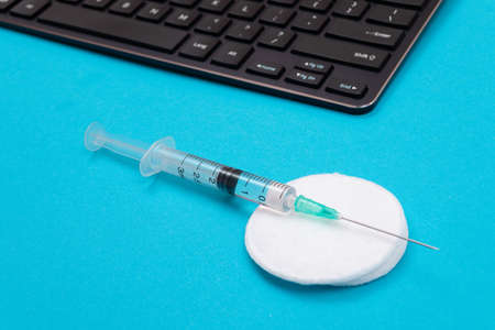 Vaccination, Immunology or Revaccination Concept - A Medical Syringe Lying on Blue Table in Doctors Office in a Hospital or Clinicの写真素材