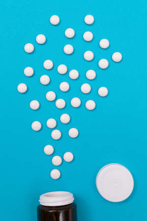 Global Pharmaceutical Industry and Medicinal Products - White Pills or Tablets Scattered from the Bottle, Lying on Blue Background, Top View, Flat Layの写真素材