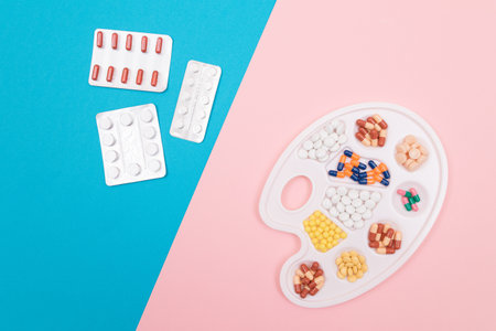 Global Pharmaceutical Industry and Medicinal Products - Different Colored Pills, Tablets and Capsules on White Art Palette with Pill Packages Lying on Split Blue and Pink Background, Flat Layの写真素材