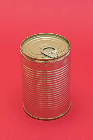 Unopened Tin Can with Blank Edge on Red Background. Canned Food. Aluminum Can for Safe and Long Term Storage of Food. Steel Sealed Food Storage Containerの写真素材