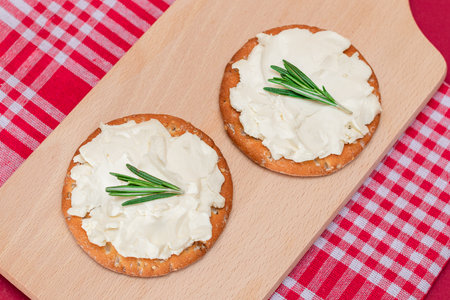 Crispy Cracker Sandwich with Cream Cheese and Rosemary on Wooden Cooking Board on Magenta Backgroundの写真素材