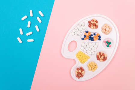 Global Pharmaceutical Industry and Medicinal Products - Different Colored Pills, Tablets and Capsules on White Art Palette Lying on Split Blue and Pink Background, Flat Layの写真素材