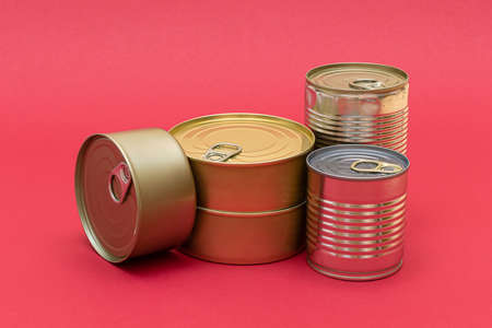 A Group of Stacked Tin Cans with Blank Edges on Red Background. Canned Food. Different Aluminum Cans for Safe and Long Term Storage of Food. Steel Sealed Food Storage Containersの写真素材