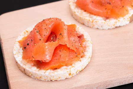 Tasty Rice Cake Sandwiches with Fresh Salmon Slices on Cutting Board - Close-Up. Easy Breakfast and Diet Food. Crispbread with Red Fish. Healthy Dietary Snackの写真素材