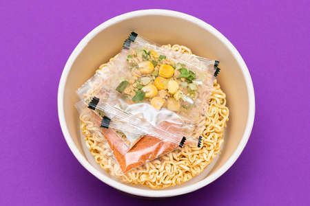 Opened Package with Uncooked Instant Noodles on Violet Background. Raw Pasta. Dry Asian Fast Food. Quick Lunchの写真素材