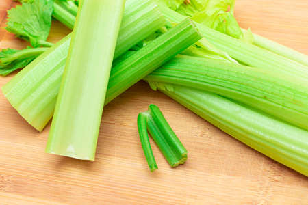 Fresh Celery Stem and Chopped Celery Sticks on Wooden Cutting Board. Vegan and Vegetarian Culture. Raw Food. Healthy Diet with Negative Calorie Content. Slimming Foodの写真素材