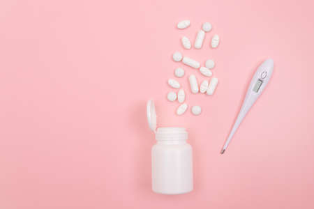 White Pills or Tablets with Electronic Thermometer on Pink Background. Pharmaceutical Industry and Medicinal Productsの写真素材