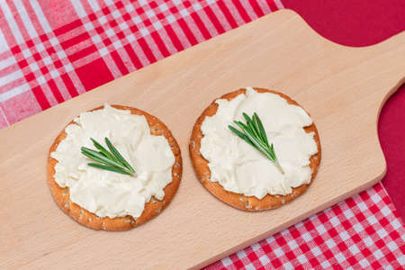 Crispy Cracker Sandwich with Cream Cheese and Rosemary on Wooden Cooking Board on Magenta Backgroundの写真素材
