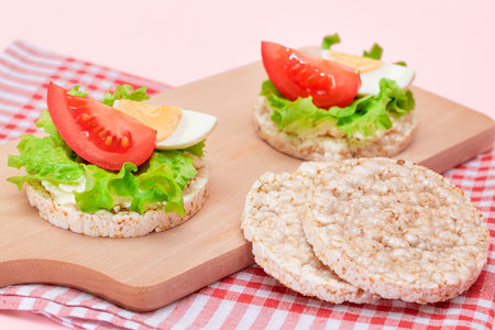 Rice Cake Sandwiches with Tomato, Lettuce and Egg on Wooden Cutting Board. Easy Breakfast. Diet Food. Quick and Healthy Sandwiches. Crispbread with Tasty Filling. Healthy Dietary Snackの写真素材