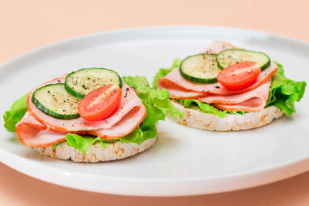 Light Breakfast. Quick and Healthy Sandwiches. Rice Cakes with Ham, Tomato, Fresh Cucumber and Green Salad on White Dishの写真素材