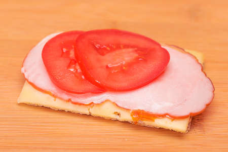 Whole Grain Crispbread with Tomato, Ham and Cheese on Bamboo Cutting Board. Easy Breakfast. Quick and Healthy Sandwiches. Crispbread with Tasty Filling. Healthy Dietary Snackの写真素材
