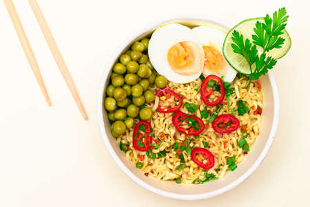 Beautiful Noodle Dish with Green Pea, Eggs, Red Hot Pepper and Greens with Chopsticks on White Background. Instant Noodles - Top Viewの写真素材