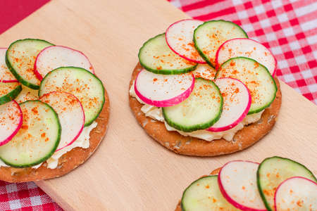 Light Breakfast or Diet Eating - Crispy Cracker Sandwich with Cream Cheese, Fresh Cucumber and Radish on Wooden Cooking Board on Magenta Backgroundの写真素材