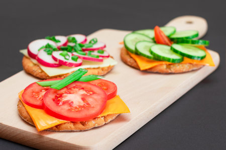Different Cracker Sandwiches with Tomato, Cucumber, Radish and Cheese on Cutting Board. Easy Breakfast. Diet Food. Quick and Healthy Sandwiches. Crispbread with Tasty Filling. Healthy Dietary Snackの写真素材