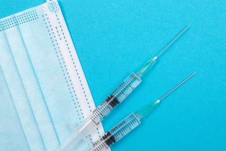 Several Syringe and Face Mask on Blue Table - Top View. Syringes are Prepared for Vaccination or Injection. Medical Experiment. Blue Disposable Medical Mask. Virus protection - Flat Layの写真素材
