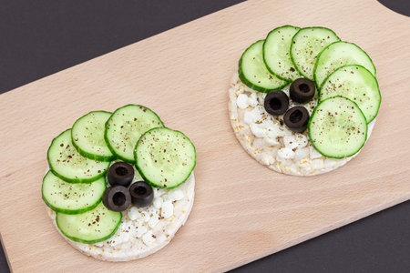Rice Cake Sandwiches with Fresh Cucumber, Cottage Cheese and Olives on Cutting Board. Easy Breakfast. Diet Food. Quick and Healthy Sandwiches. Crispbread with Tasty Filling. Healthy Dietary Snackの写真素材