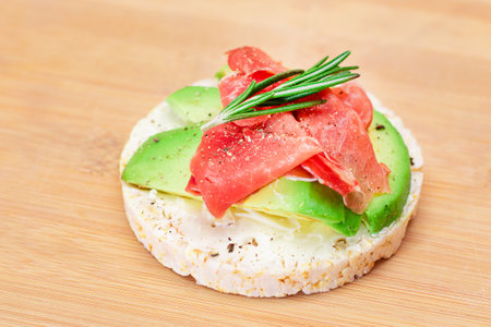 Rice Cake Sandwich with Fresh Avocado, Jamon and Rosemary on Bamboo Cutting Board. Easy Breakfast. Diet Food. Quick and Healthy Sandwiches. Crispbread with Tasty Filling. Healthy Dietary Snackの写真素材