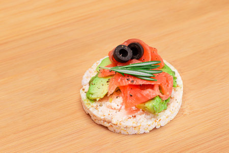 Rice Cake Sandwich with Fresh Salmon, Avocado and Olives on Bamboo Cutting Board. Easy Breakfast. Diet Food. Quick and Healthy Sandwiches. Crispbread with Tasty Filling. Healthy Dietary Snackの写真素材