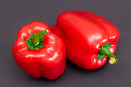 Two Fresh Red Sweet Bell Peppers on Black Backgroundの写真素材