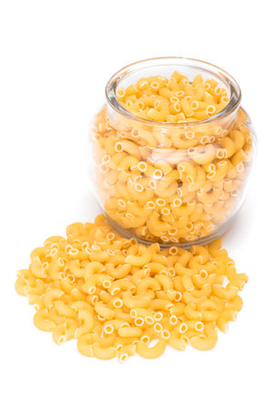 Uncooked Chifferi Rigati Pasta in Glass Jar Isolated on White Background. Fat and Unhealthy Food. Scattered Classic Dry Macaroni. Italian Culture and Cuisine. Raw Pastaの写真素材