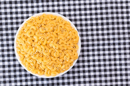 Uncooked Chifferi Rigati Pasta in White Cup on Black Checkered Towel. Fat and Unhealthy Food. Classic Dry Macaroni. Italian Culture and Cuisine. Raw Pastaの写真素材